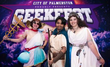 Image: 3 youth dressed up in front of the Geekfest Top End photodrop
